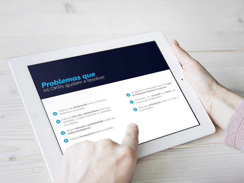 ebook okr, guia definitivo de okr, coblue okr. maos segurando um tablete com um e book com os dizeres "problemas que os okrs ajudam a resolver"